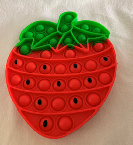 Red and green strawberry popit with black seeds on some of the dimples. Sensory fidget toy.